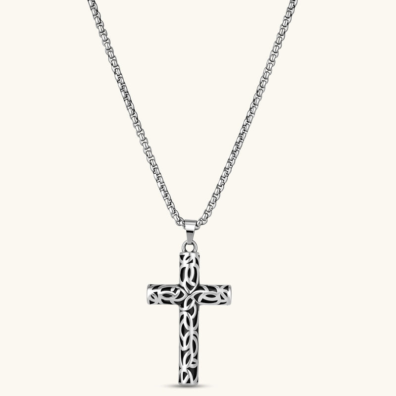 Silver stainless steel Celtic cross pendant with filigree vine pattern on a box chain, against a cream background.