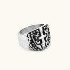 Silver 316L stainless steel men's signet ring with raised knight shield, cross motif, and ornate blackened scrollwork detailing.
