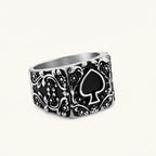 Silver-tone 316L stainless steel signet ring with black enamel spade motif and intricate floral scrollwork relief detail.