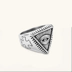 Silver stainless steel signet ring with engraved all-seeing eye in triangle, radiating lines, and cross motifs on the band.