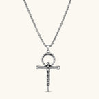 Silver stainless steel ankh pendant with skull motifs on vertical bar and textured ring top, on a box chain necklace.