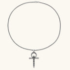 Silver stainless steel ankh pendant with skull motifs on vertical bar and textured ring top, on a box chain necklace.