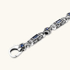 Additional angle of the stainless steel link bracelet with blue CZ stones and baroque scroll engravings.