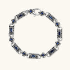 Alternate angle of the stainless steel link bracelet with blue CZ stones and baroque scroll engravings.