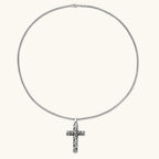 Silver stainless steel Celtic cross pendant with filigree vine pattern on a box chain, against a cream background.
