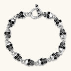 Silver stainless steel bracelet with linked 3D skull charms and a spring-ring clasp, oxidized black detailing, 225mm length.