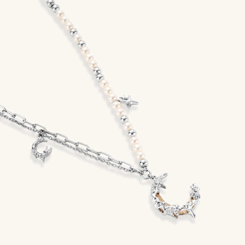 Additional angle of the silver-toned crescent moon pendant with star accents and a single pearl bead on a fine chain.