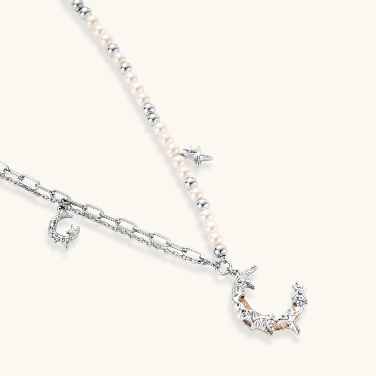 Additional angle of the silver-toned crescent moon pendant with star accents and a single pearl bead on a fine chain.