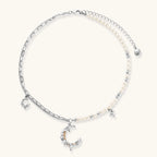Alternate angle of the silver-toned crescent moon pendant with star accents and a single pearl bead on a fine chain.