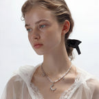 Detail view of the silver-toned crescent moon pendant with star accents and a single pearl bead on a fine chain.