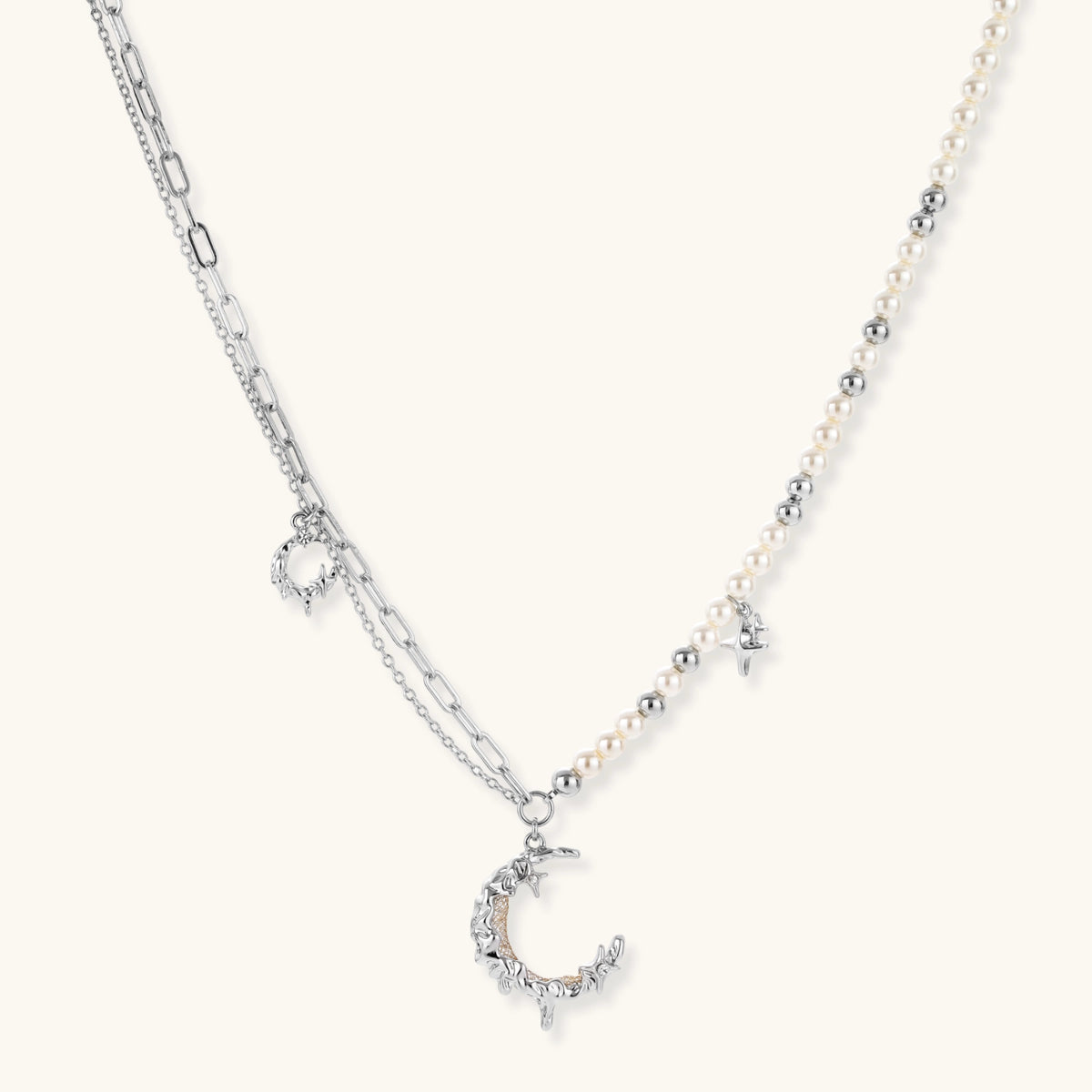 Front view of the silver-toned crescent moon pendant with star accents and a single pearl bead on a fine chain.