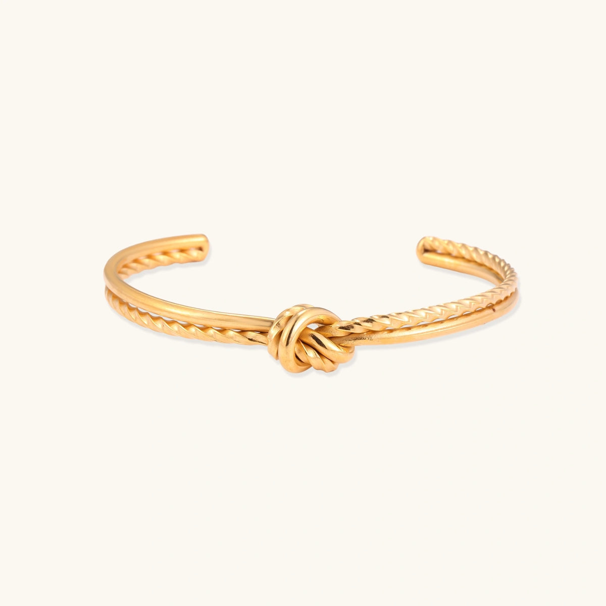 Front view of the gold-plated cuff bracelet with twisted rope texture and a knot centerpiece.