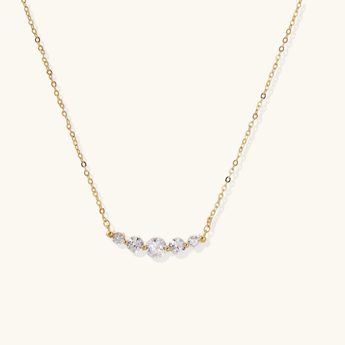 Front view of the 14K gold-plated necklace with five curved zirconia stones on a fine chain.