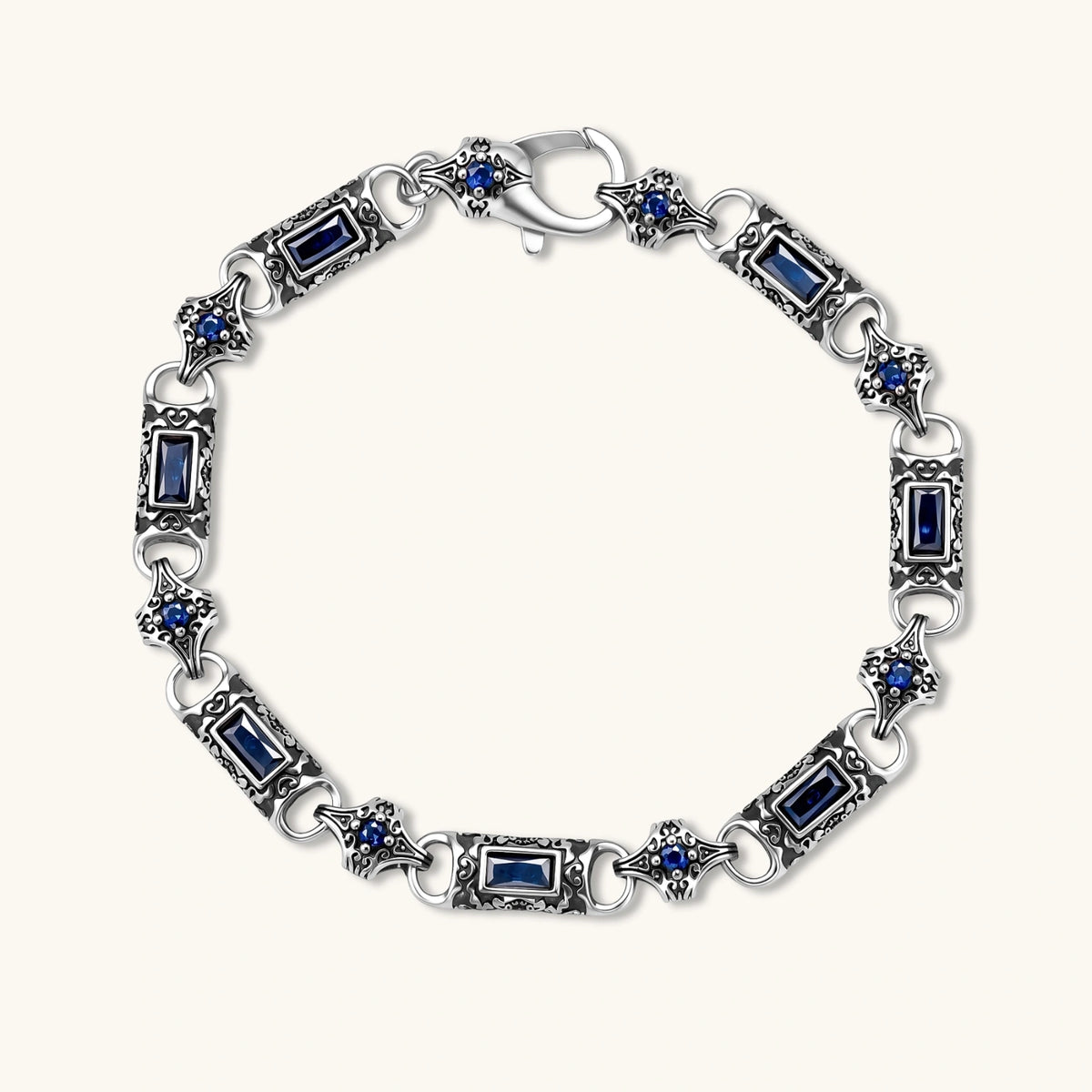 Alternate angle of the stainless steel link bracelet with blue CZ stones and baroque scroll engravings.