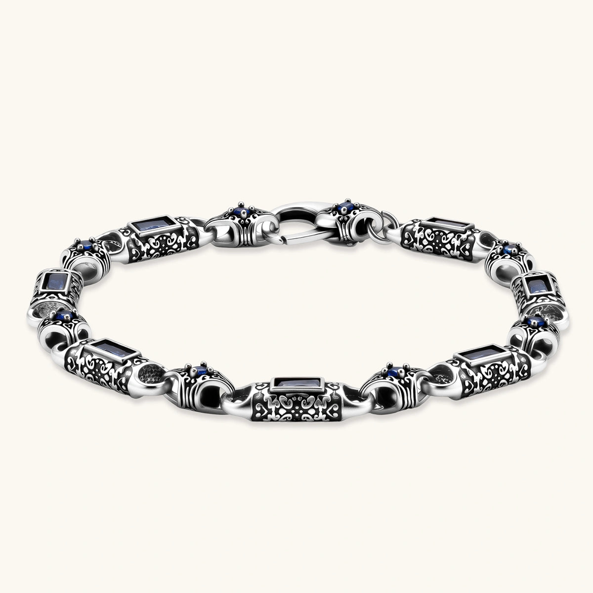 Front view of the stainless steel link bracelet with blue CZ stones and baroque scroll engravings.