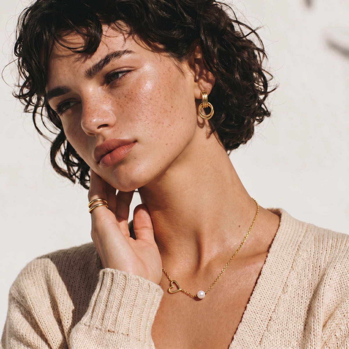 Detail view of the gold asymmetric open heart charm with a single pearl bead on a fine chain.